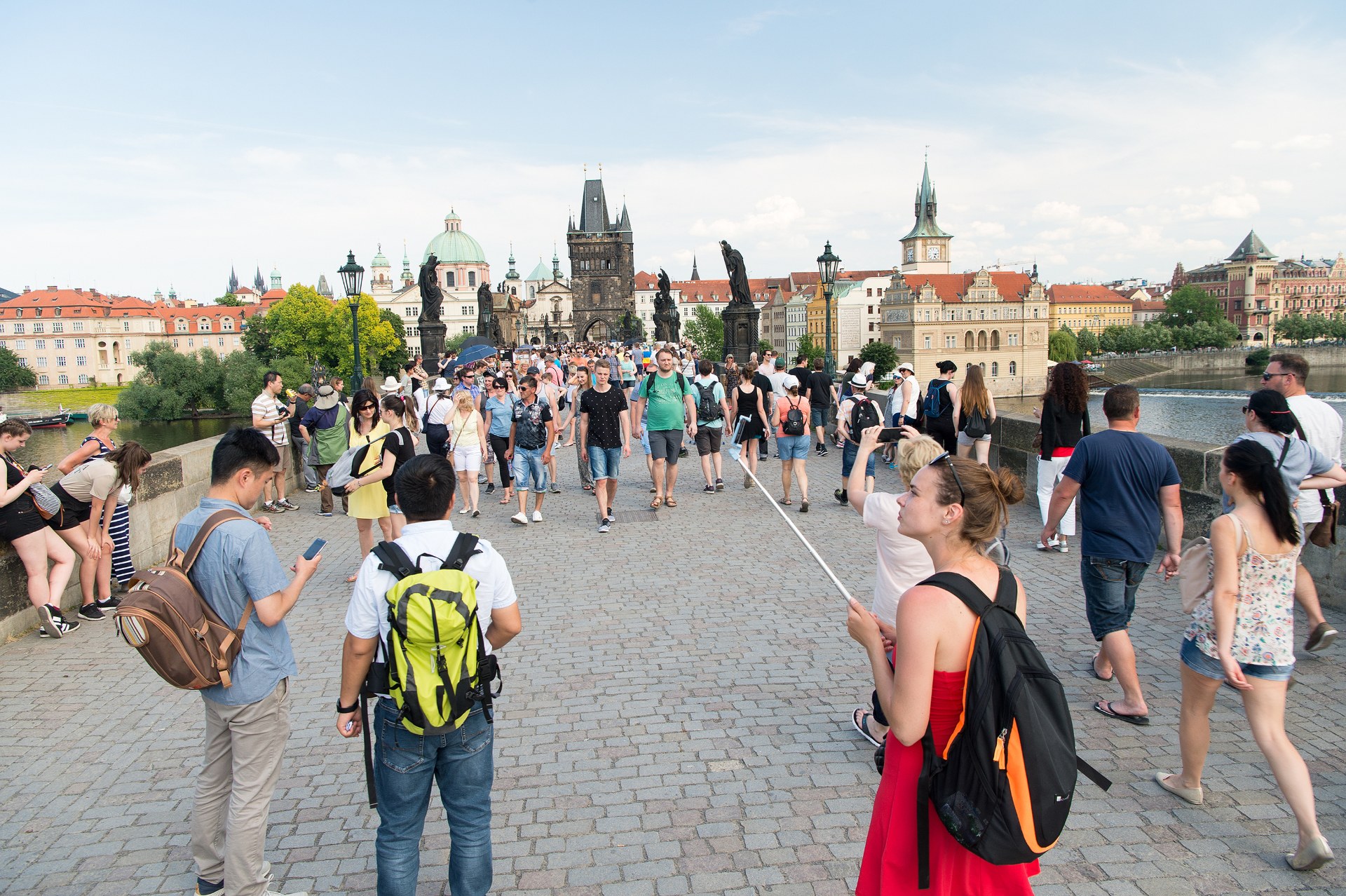Hátizsákos fiatalok sétálnak át a prágai Károly hídon, mögöttük az óvárosi hídtorony